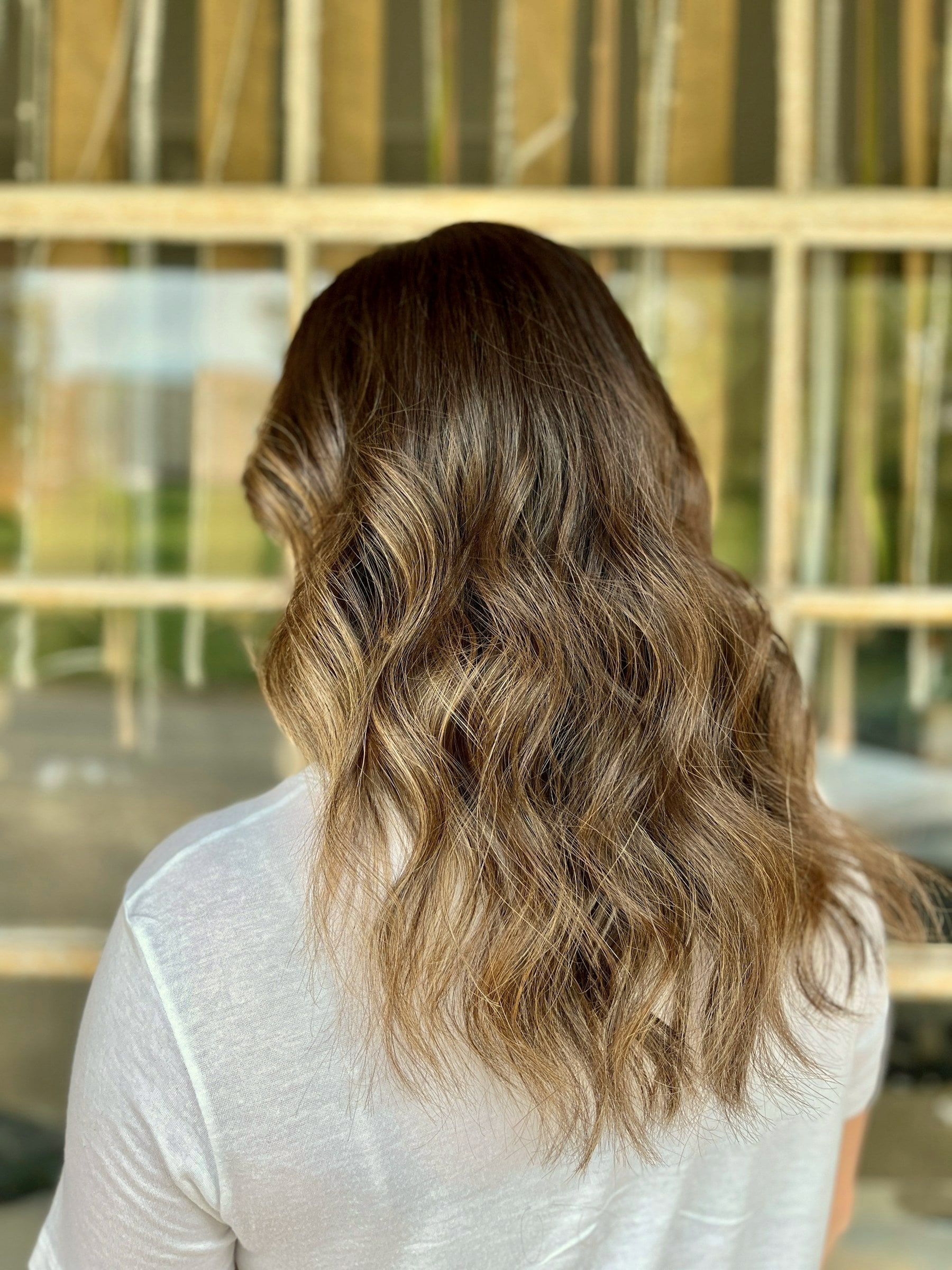 Langes Haar mit honigfarbener Balayage in weichen Wellen, von hinten